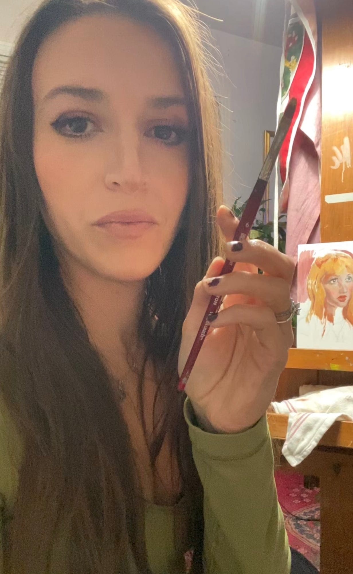 Mia Cugasi holding a paintbrush in her studio